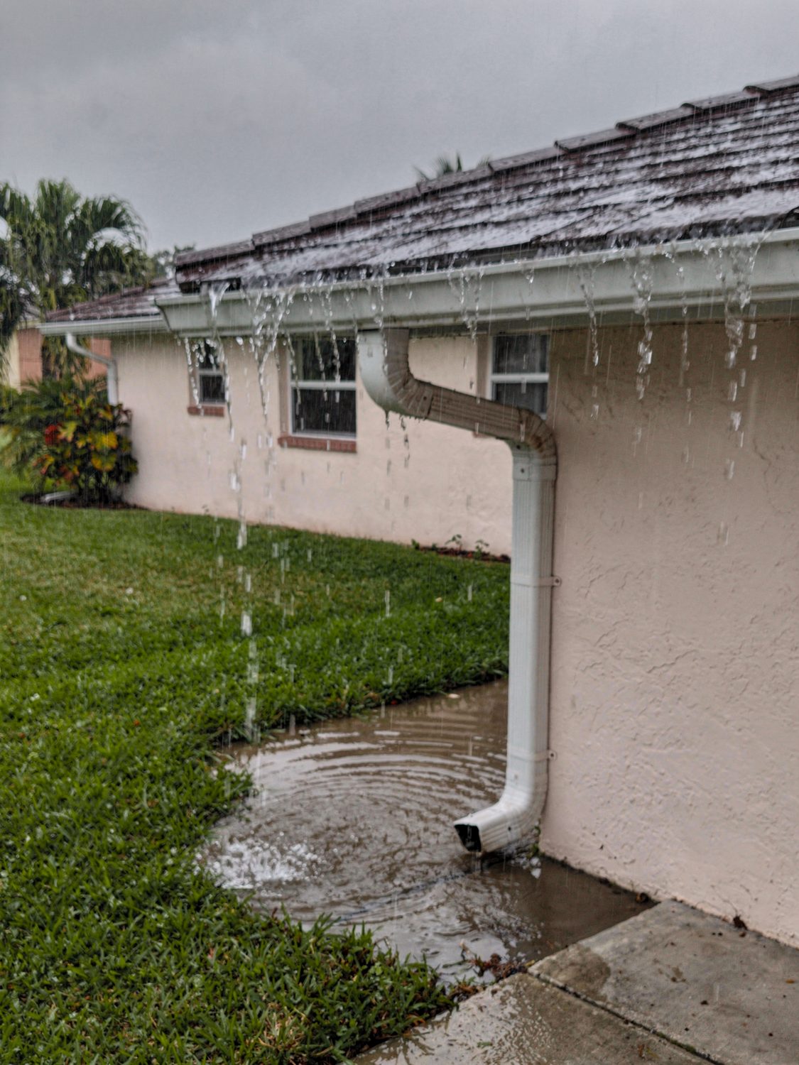 Seamless gutters channeling heavy rain away from a Naples, FL home